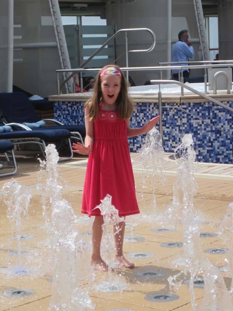 Young girl in red dress standing in fountain on Celebrity Equinox.