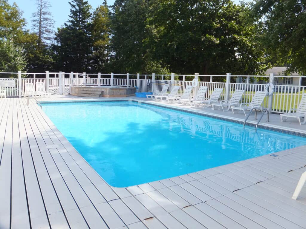 Rectangular swimming pool, deck chairs and hot tub at Kindred Spirits Country Inn & Cottages.