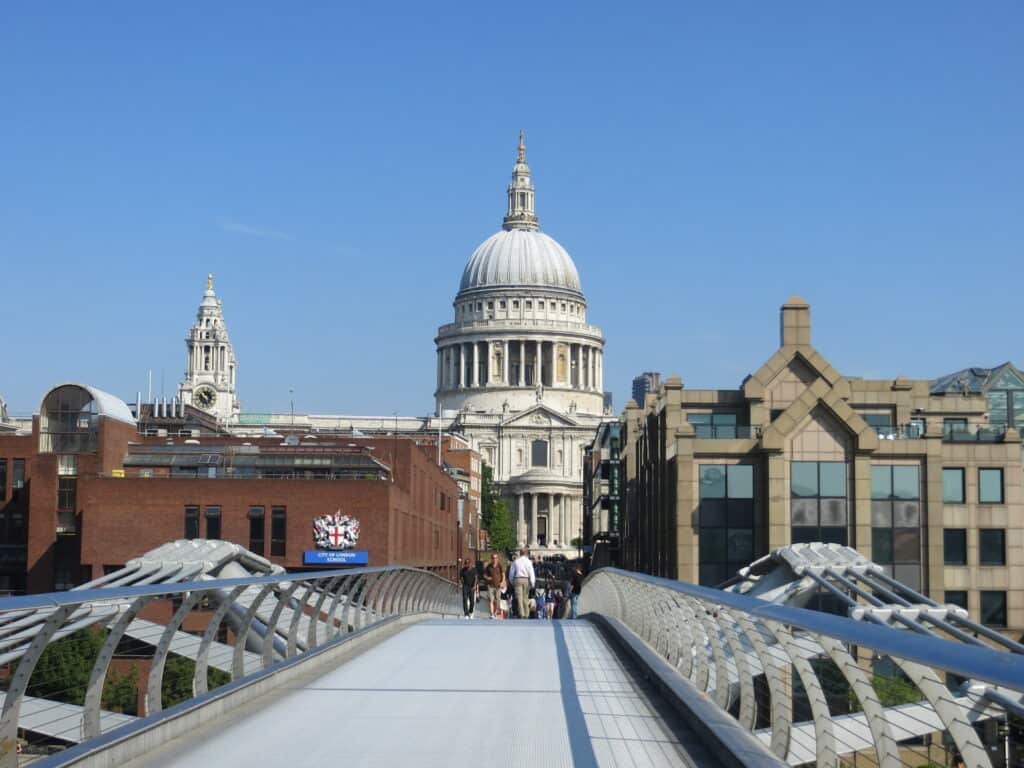 View of St. Paul's Cathedral from Millennium Bridge set against blue sky.