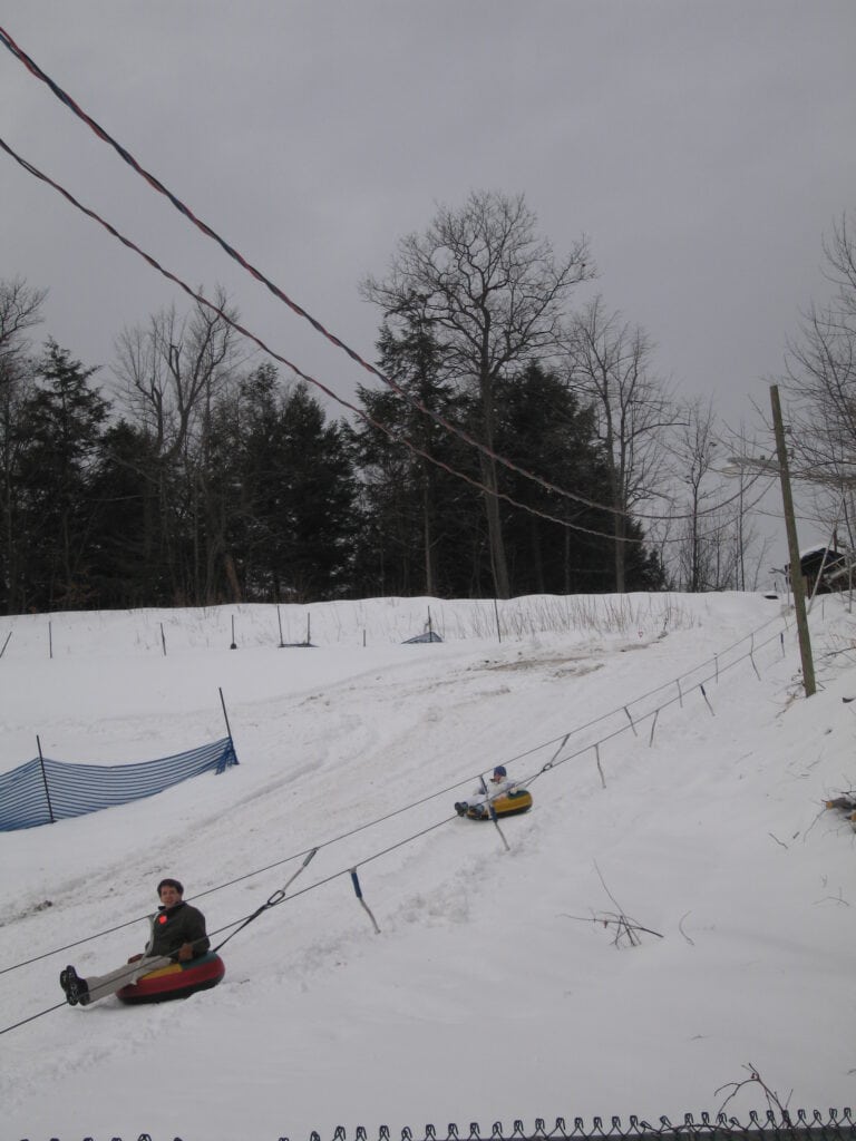 Dad and daughter riding tubes down snowy hill at Montebello.