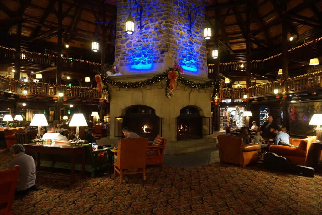 Large stone fireplace surrounded by chairs, tables and lamps in lobby of the Fairmont Chateau Montebello in Quebec.