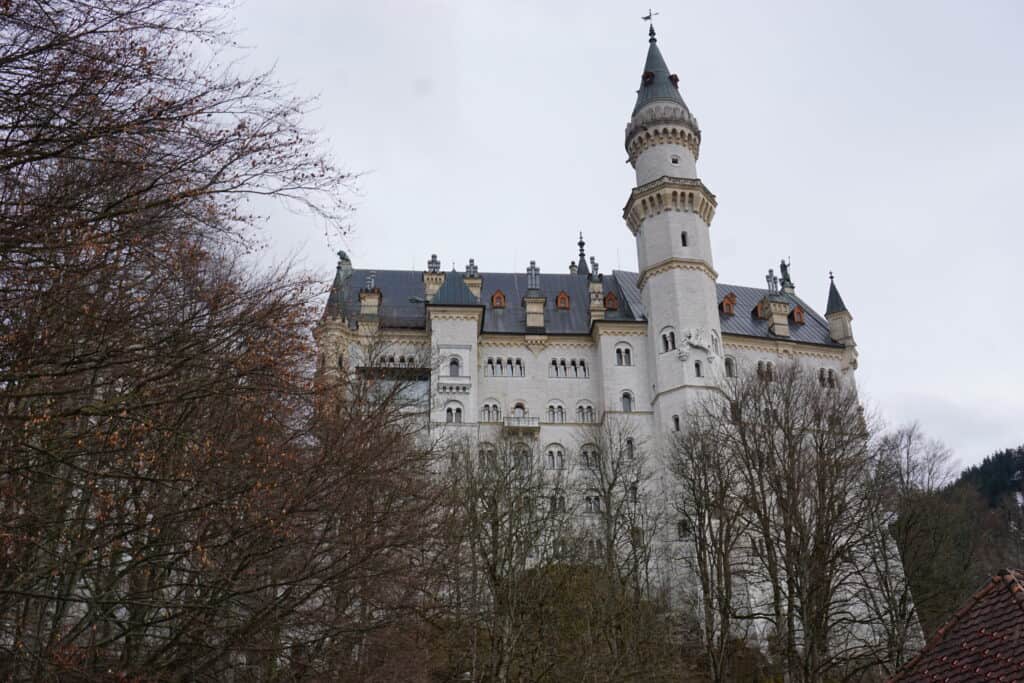 Exterior of Neuschwanstein Castle surrounded by bare trees in mid-March.