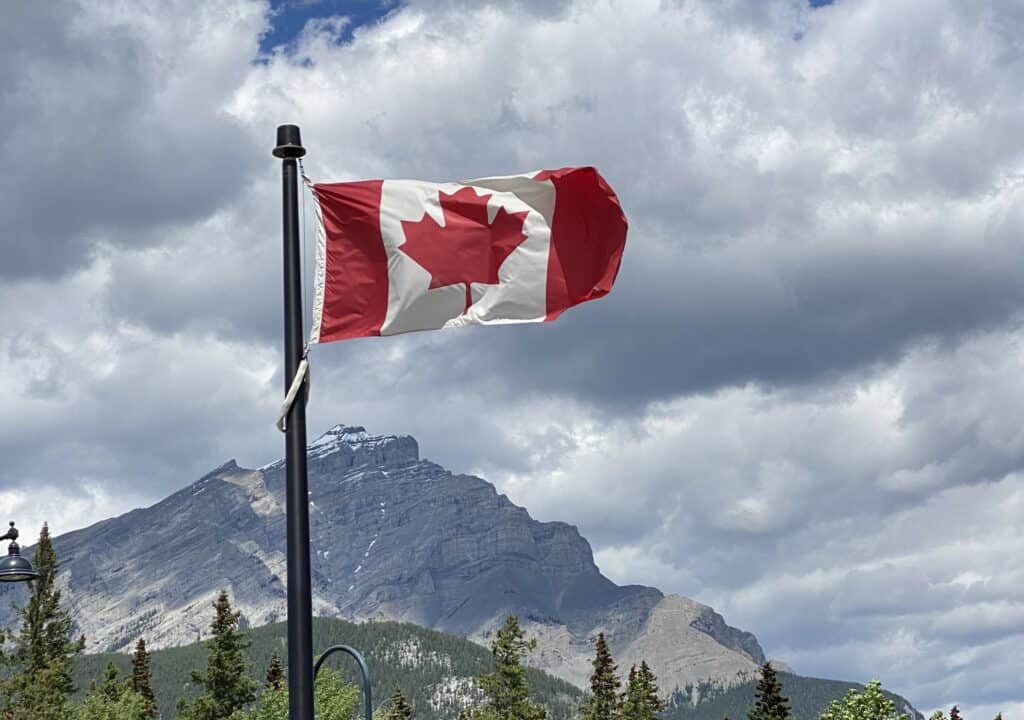 Canada flag with mountain in background on cloudy day - at upper terminal of Banff Gondola.