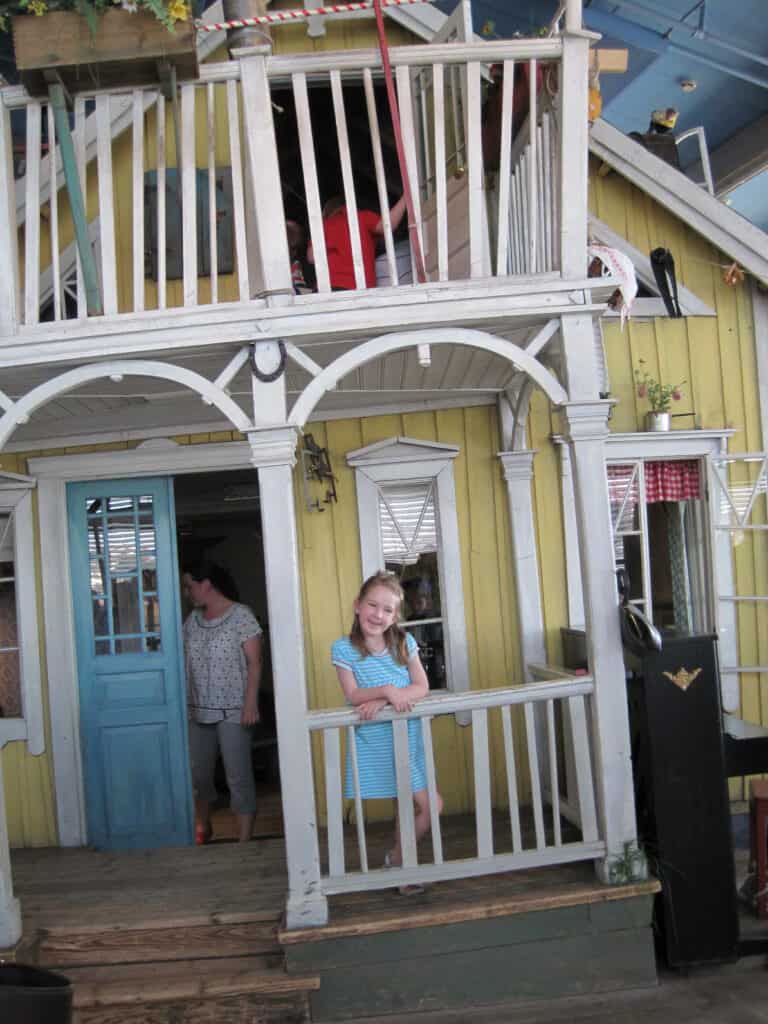 Young girl standing on porch of Villa Villekulla - Pippi Longstocking's house at Junibacken museum in Stockholm.
