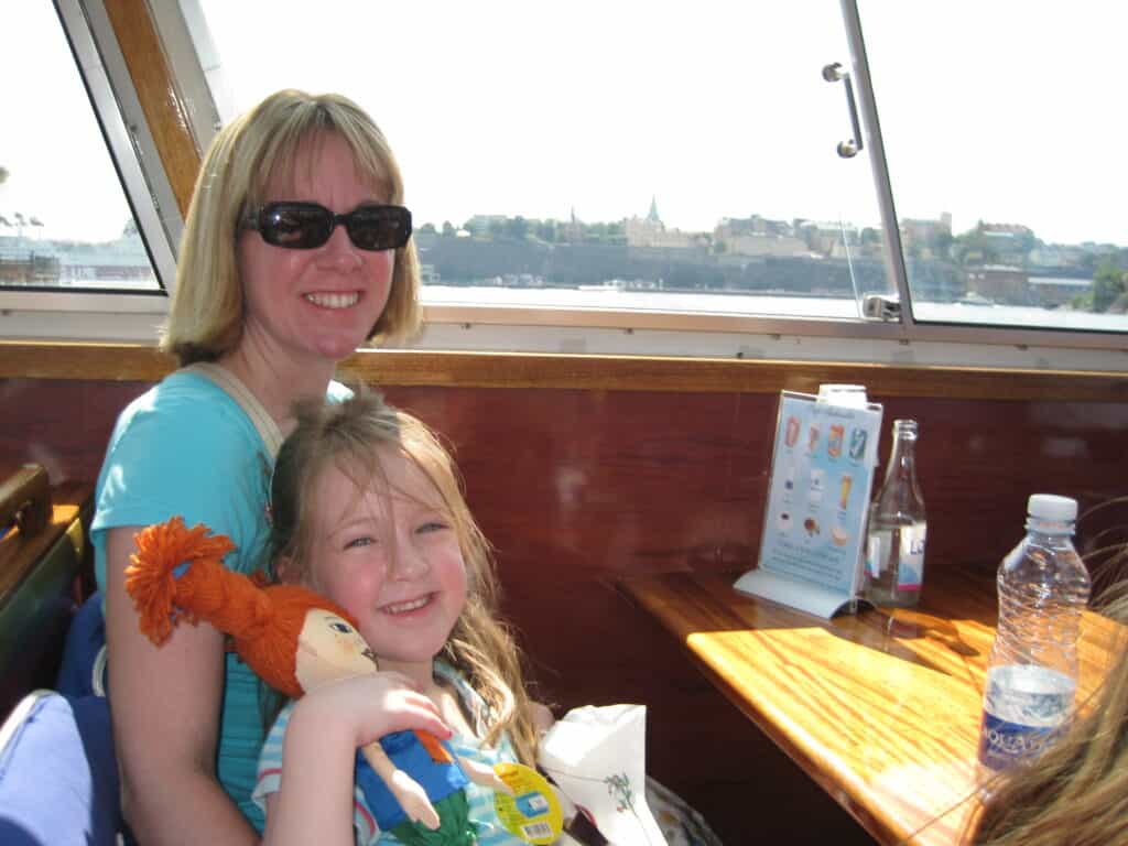 Woman and young girl holding a Pippy Longstocking rag doll sitting on a ferry in Stockholm.
