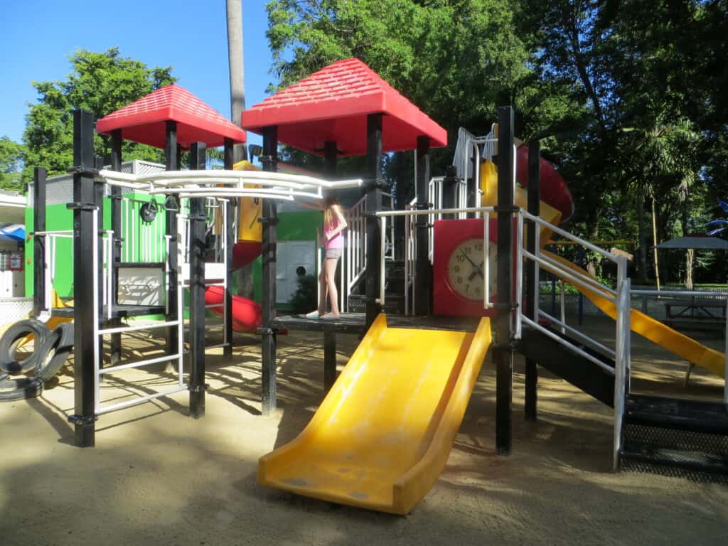 Young girl on Beaches Negril playground structure with bright yellow slide.