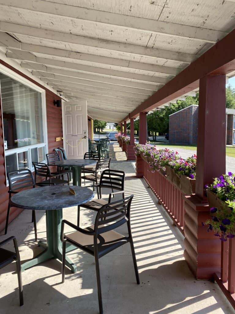 Patio of Watersedge Restaurant in Gore Bay with colourful flowerboxes along railing and black metal tables and chairs.