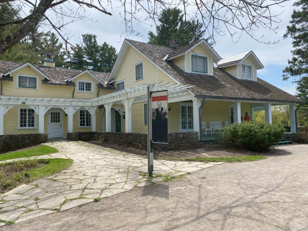 Mackenzie King Estate cottage - creamy yellow siding with white trim and covered porch.