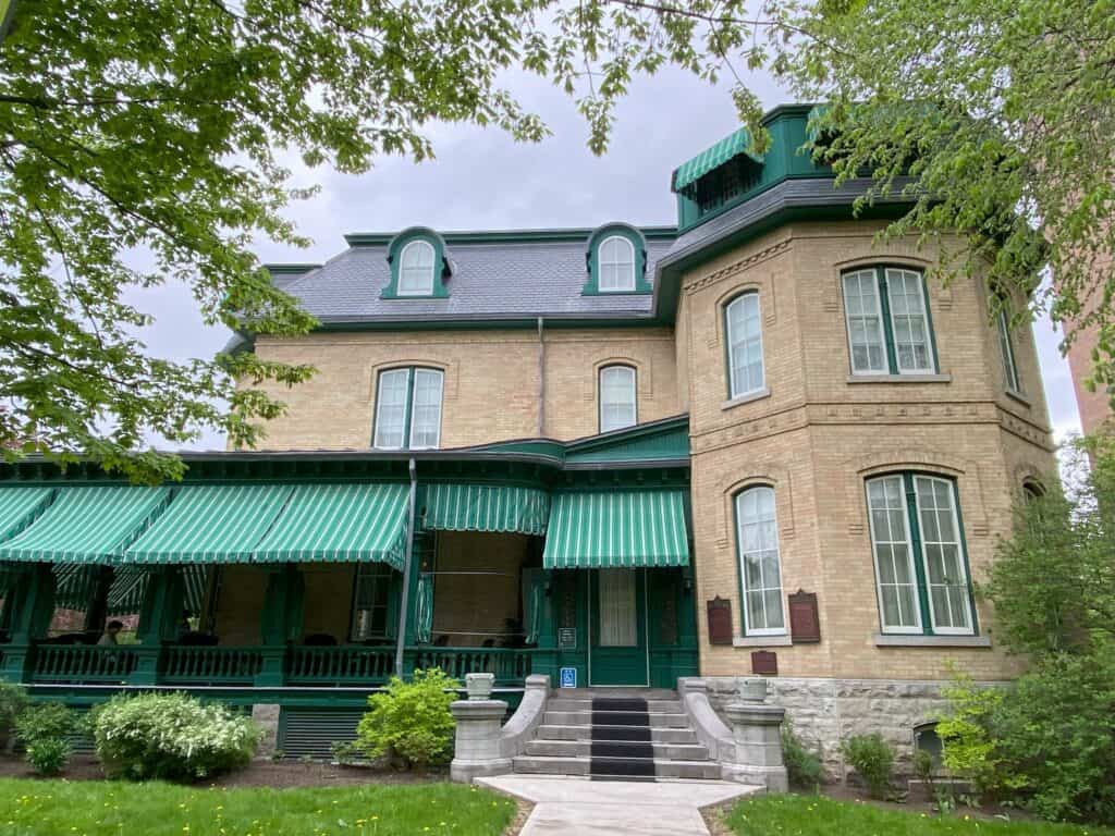 Exterior of Laurier House National Historic Site of Canada - light brown brick building with green awnings at front.