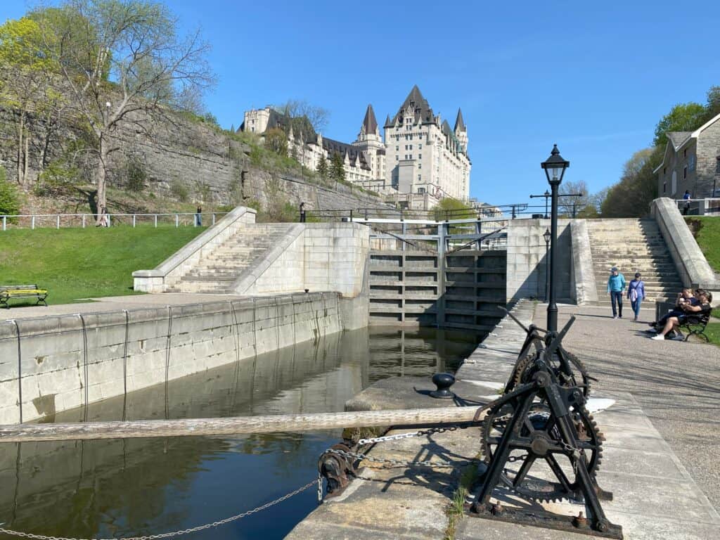 Rideau Canal locks filled with water with Chateau Laurier in background against bright blue sky.