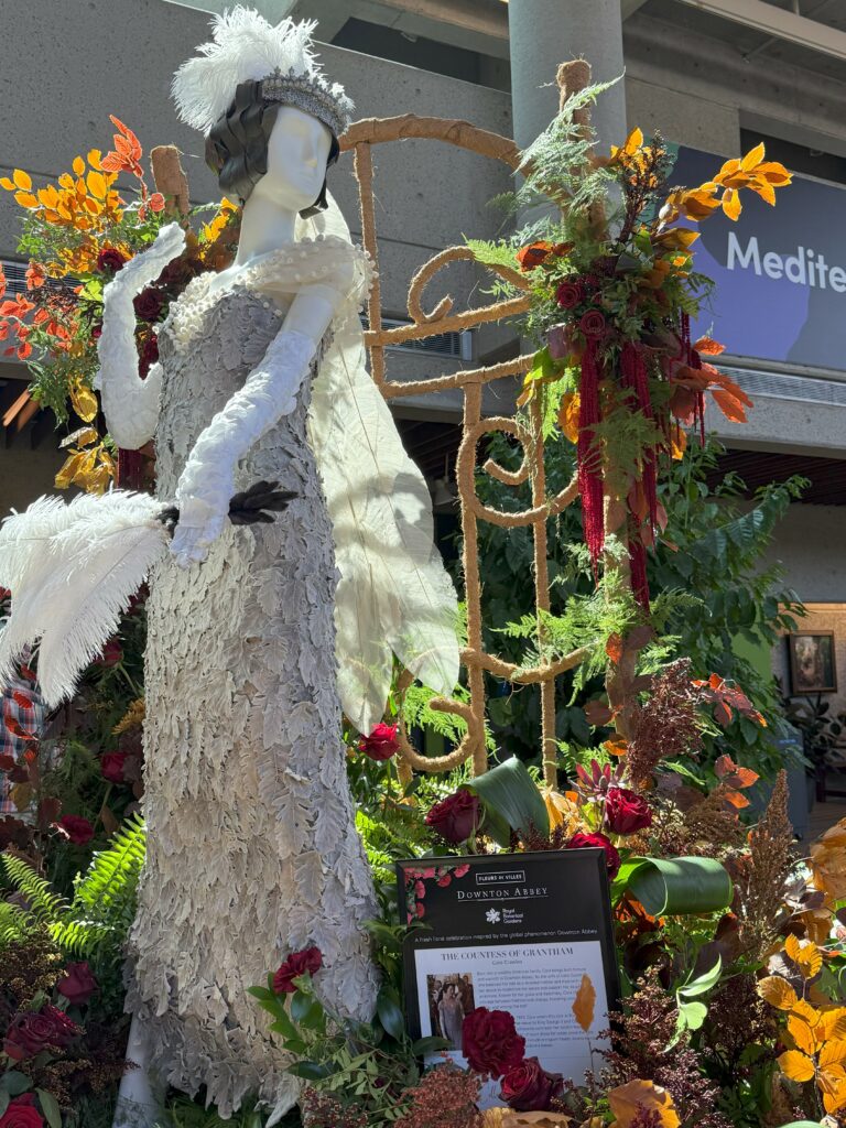 Floral mannequin - Cora Crawley - white gown - surrounded by colourful greenery.