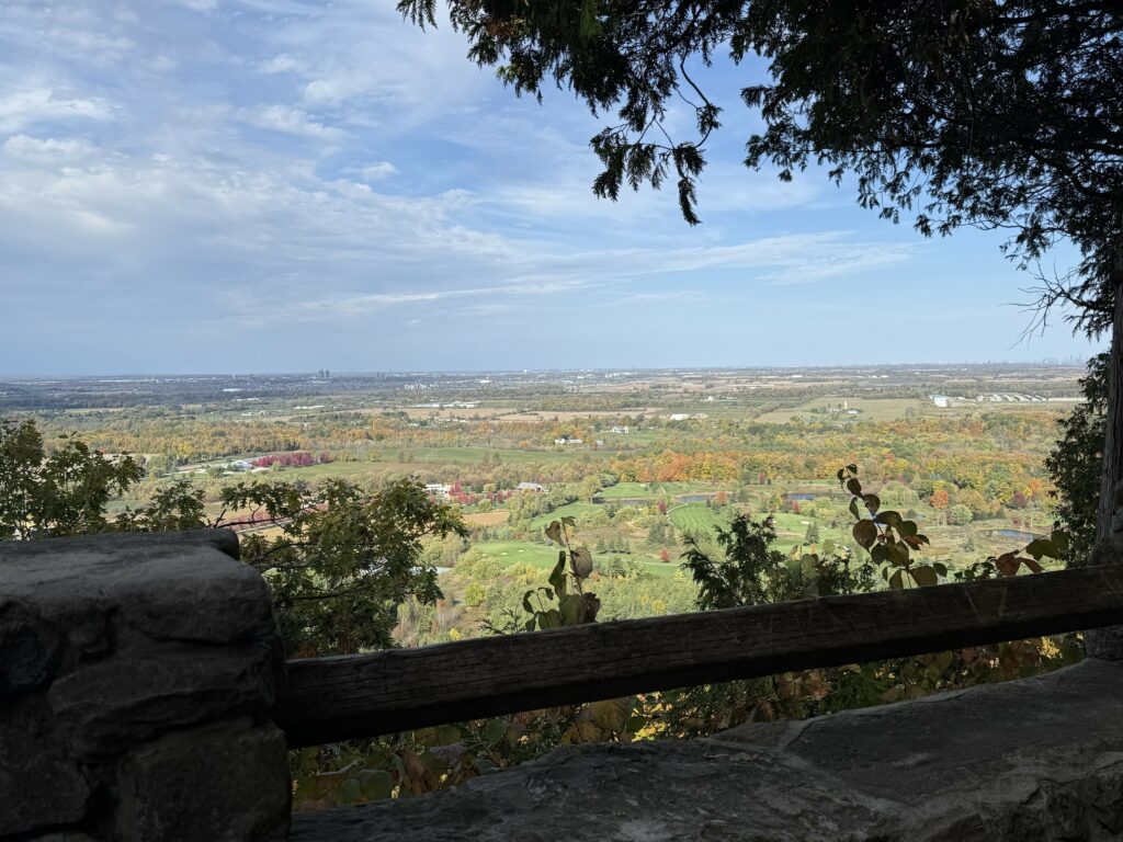 Brock Harris Lookout at Mount Nemo - stone pillar and wooden fence on edge of ravine with view across countryside on a fall day.