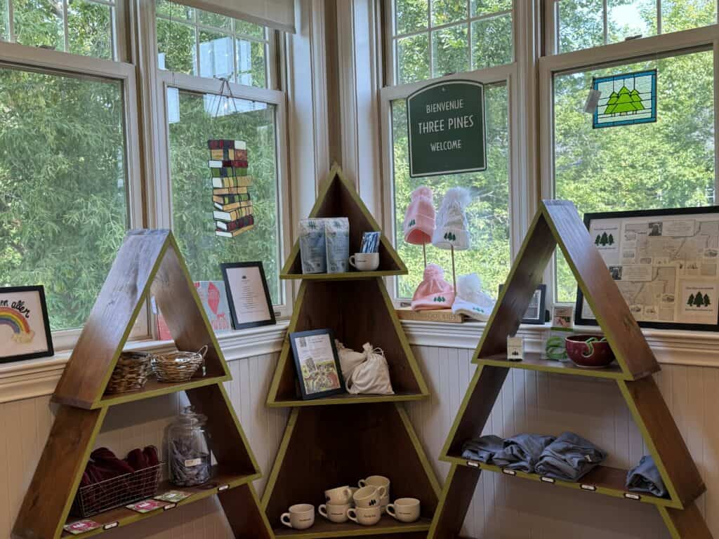 three tree shaped shelving units with Three Pines merchandise in front of windows - Brome Lake Books.