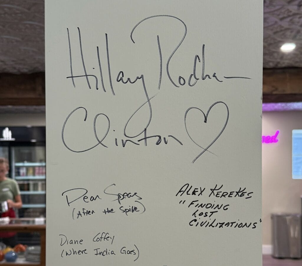 white pillar with author signatures - Hillary Rodham Clinton prominent - counter of cafe in background.