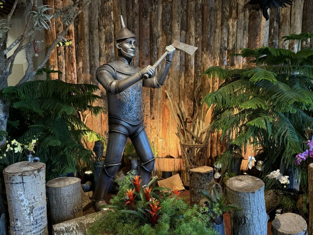 The Tin Man holding axe surrounded by foliage and flowers at the royal botanical gardens bloomland in oz exhibit.