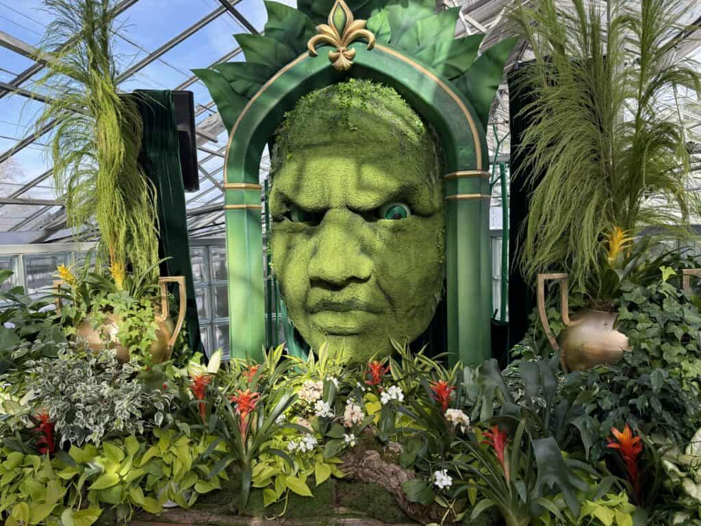 green face of wizard surrounded by plants and flowers in the mediterranean garden at royal botanical gardens.