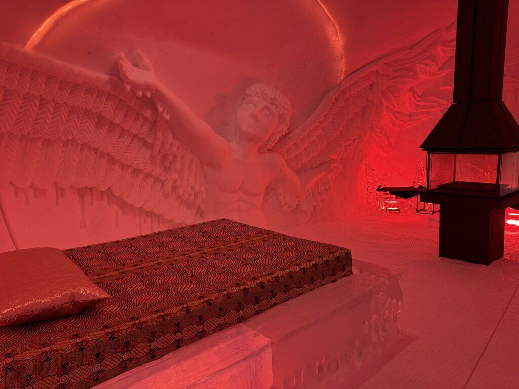 mattress and pillow on ice bed with free standing black fireplace in background.