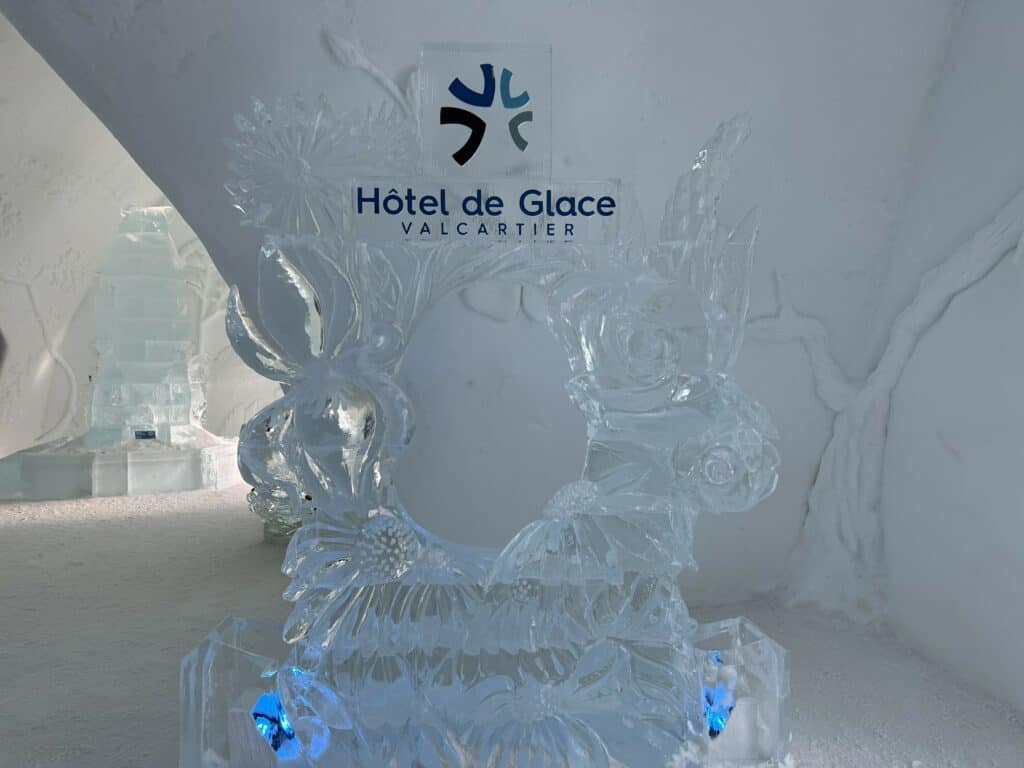 ice sculpture at the entrance to the ice hotel in Quebec City with dark blue "Hotel de Glace Valcartier" logo.