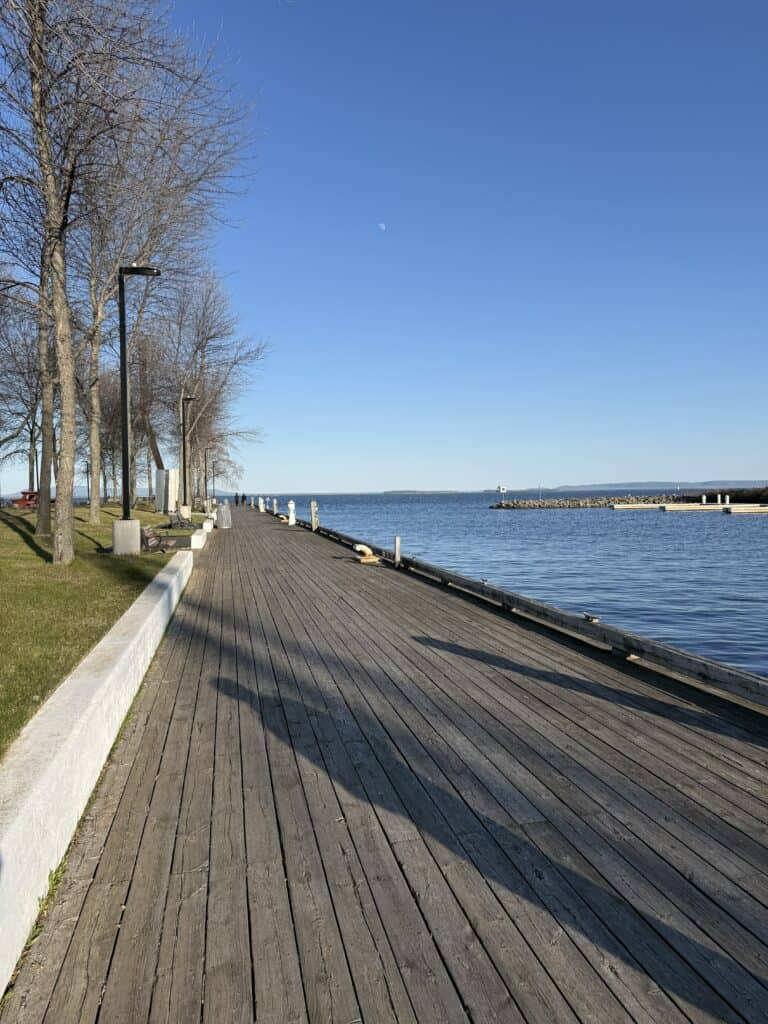 wooden boardwalk with lake on the right and park on the left.