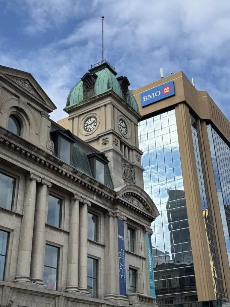 The Globe Theatre in downtown Regina with clock tower and green copper roof in front of BMO building.