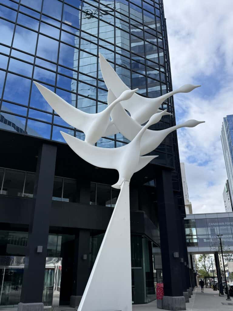white sculpture of three geese in front of glass building in downtown Regina, Saskatchewan.