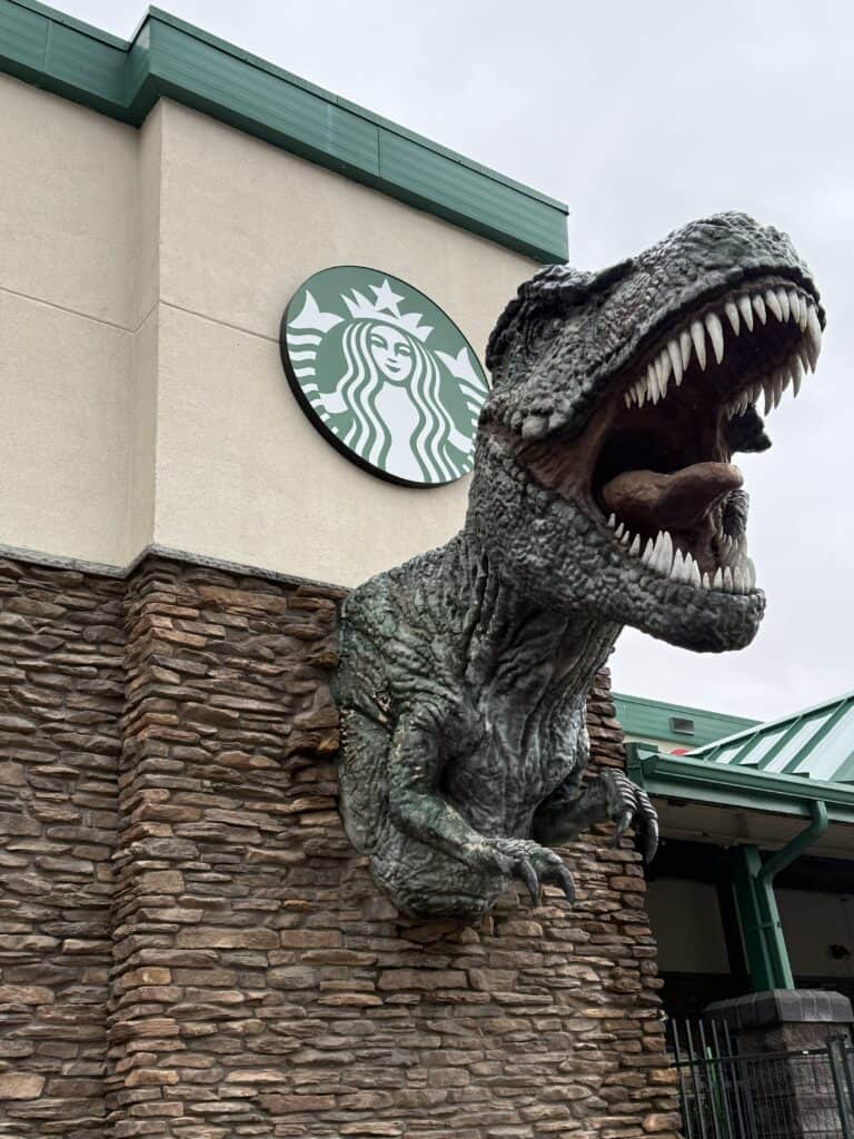 brick and stucco exterior of building with Starbucks logo and T-Rex head.