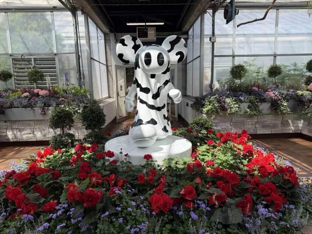 black and white anchorball figure among red flowers in breezeway at the royal botanical gardens.