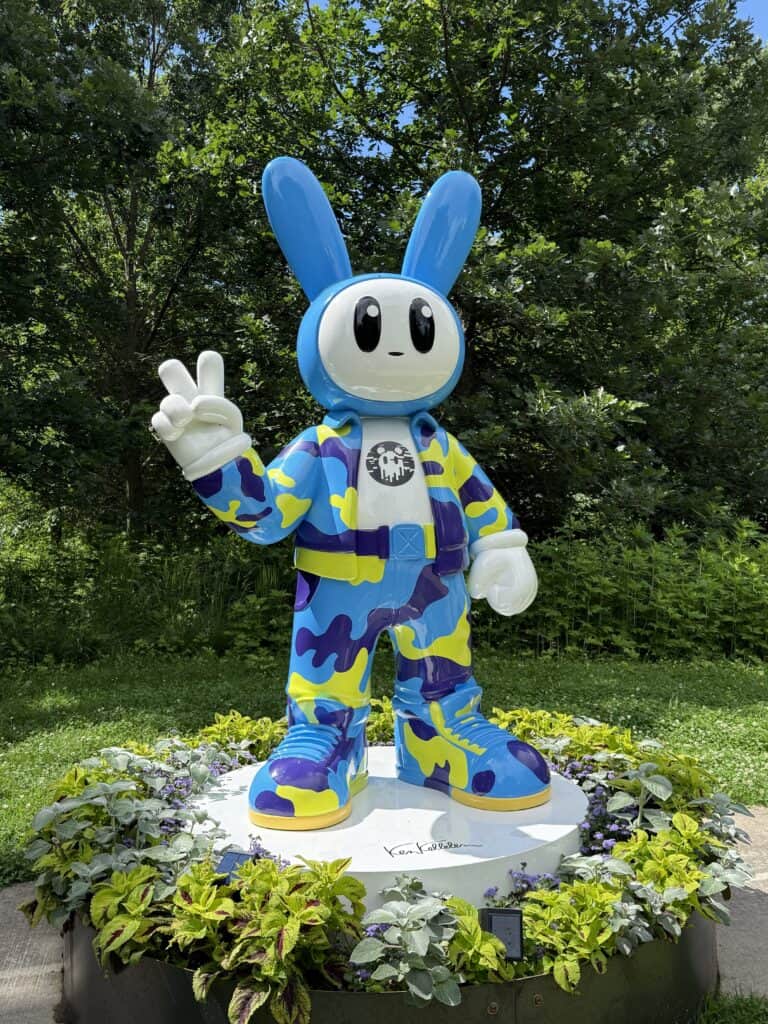 sculpture of bunny character in blue and yellow holding up two fingers.