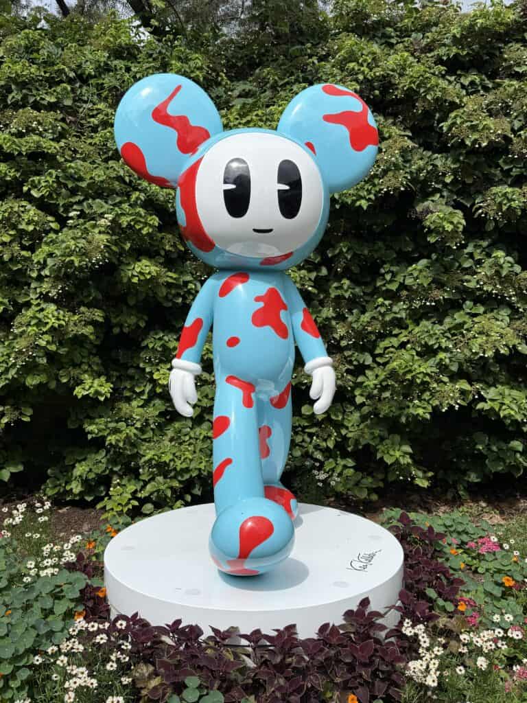 Anchorball character sculpture - Willy - light blue with red splotches, white hands and face with black eyes and mouth in walking stance.