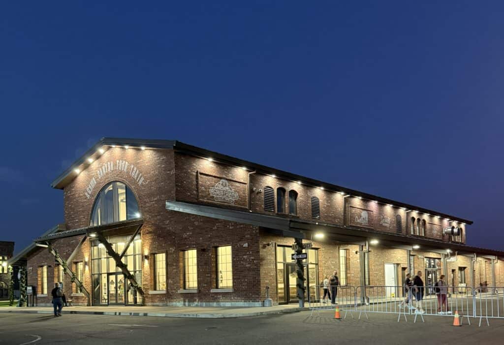 red brick and glass train depot building lit up in early morning hours set against a dark blue sky.