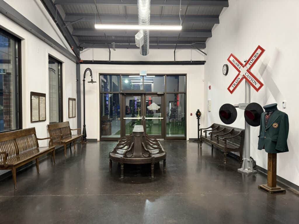interior of Agawa Canyon Tour Train depot with wooden bench seats, agawa canyon train tours rail crossing sign and uniform on display.