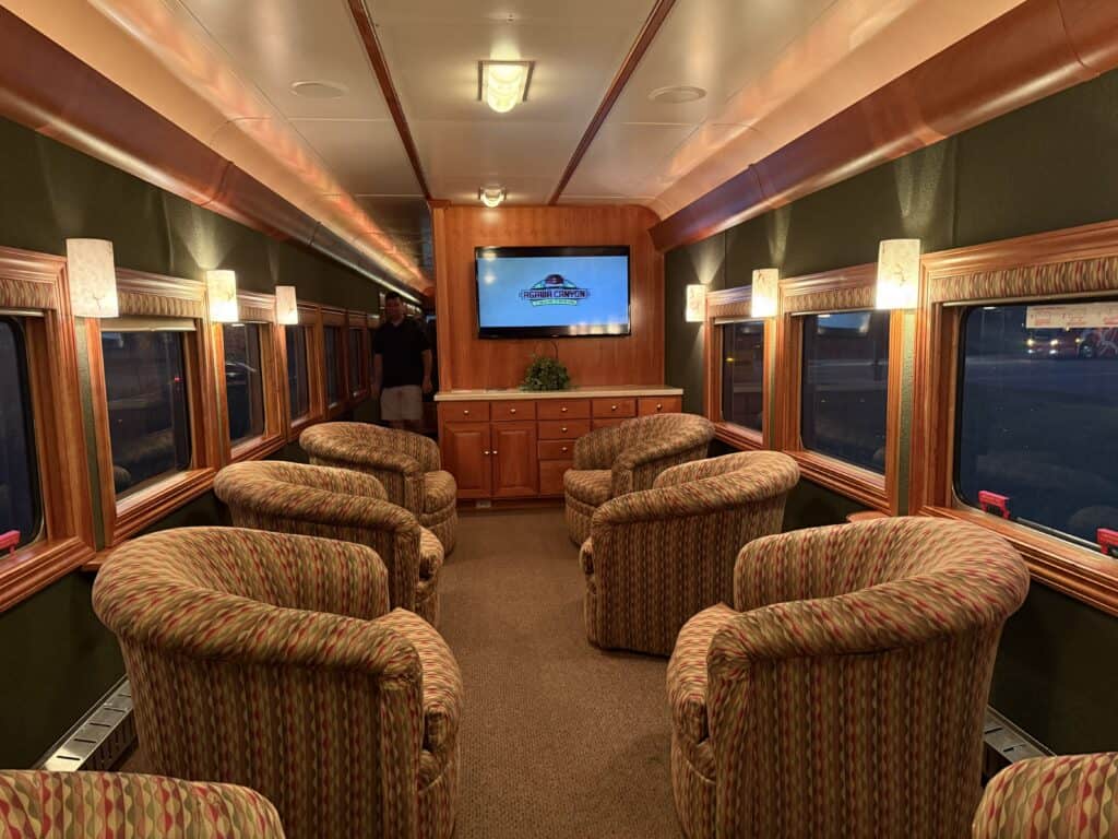agawa canyon tour train stone gardner car lounge with upholstered swivel bucket chairs and wooden counter with large television mounted.